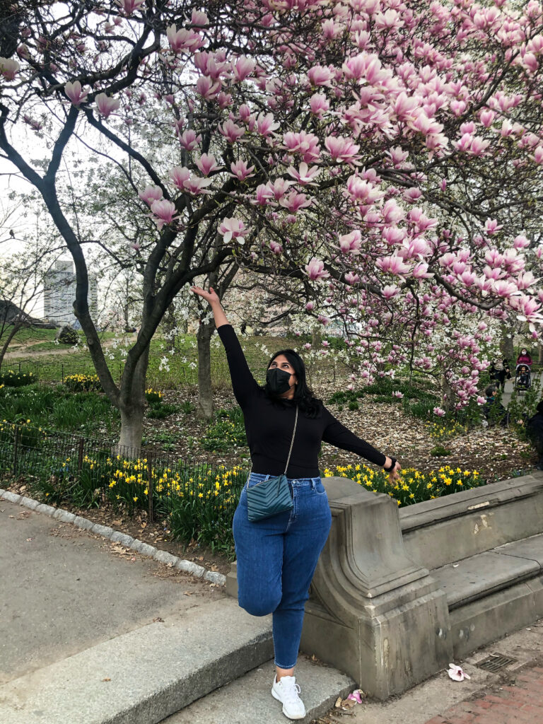 A pose idea of a girl under cherry blossom tree in Central Park, Manhattan, New York.